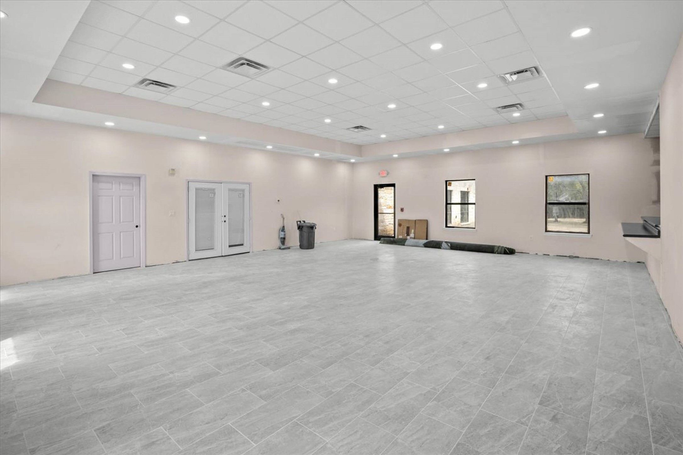 375 King Rea Spur Georgetown, TX 78633 - Photo 14 of 29 Spacious room featuring light gray floor tiles, recessed lighting, drop ceiling, multiple windows, and exterior double doors with glass panels