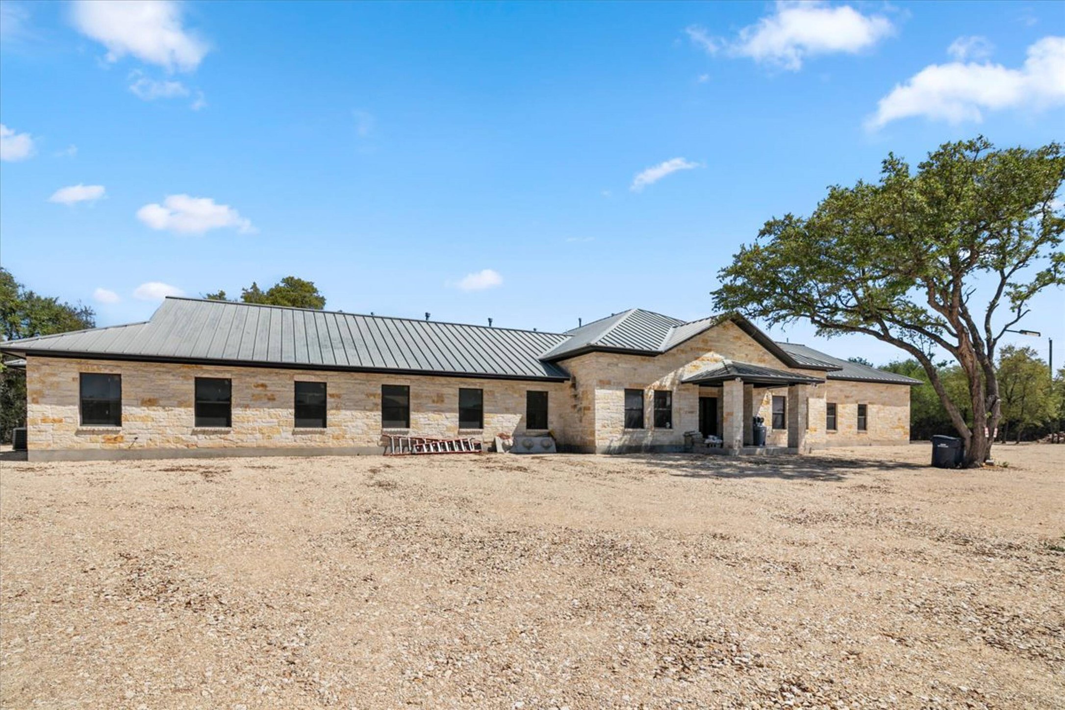 375 King Rea Spur Georgetown, TX 78633 - Photo 26 of 29 Stone veneer exterior with a metal roof and dark-framed windows