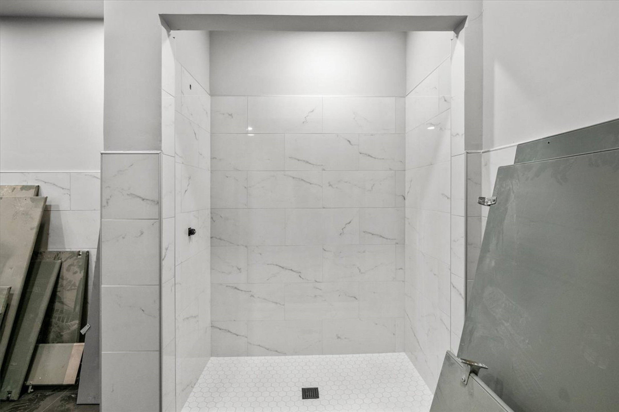 375 King Rea Spur Georgetown, TX 78633 - Photo 10 of 29 Enclosed shower stall featuring white marble-look subway tile walls, a hexagonal mosaic tile floor, and matte black plumbing fixtures