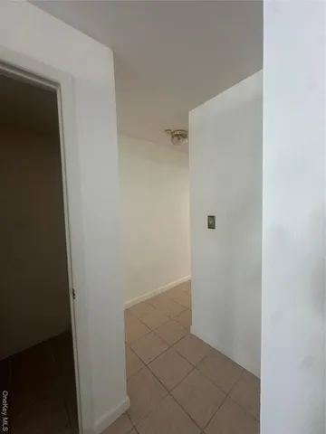 a view of a hallway with wooden floor and a bathroom