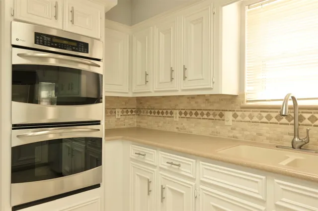 a kitchen with granite countertop white cabinets and stainless steel appliances