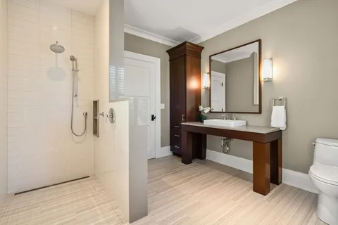 a bathroom with a toilet a sink a mirror and shower