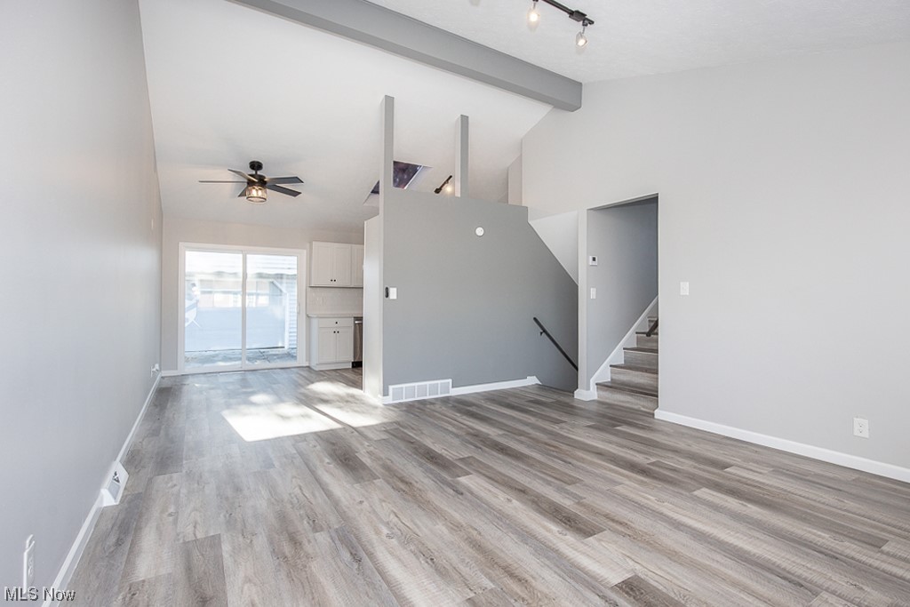  living room with light flooring, high vaulted ceiling, ceiling fan, rail lighting, and beamed ceiling