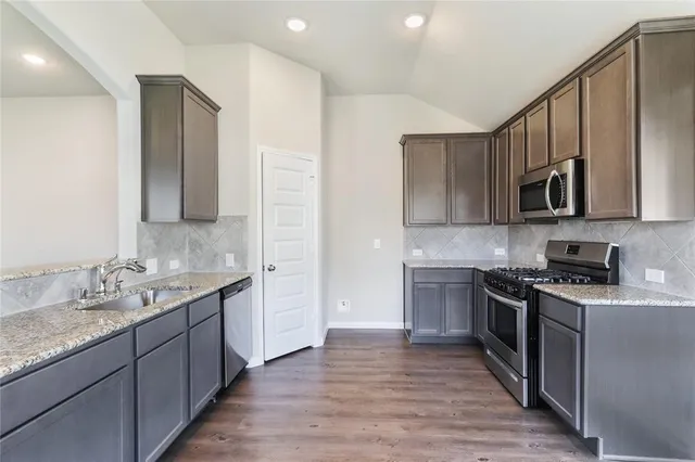 a kitchen with stainless steel appliances granite countertop wooden cabinets a stove top oven a sink and dishwasher