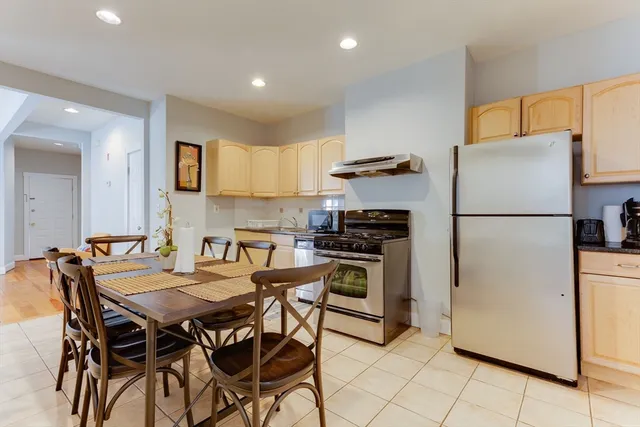 a kitchen with stainless steel appliances a refrigerator a stove a dining table and chairs