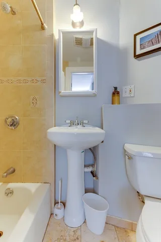 a bathroom with a sink toilet a mirror and bathtub
