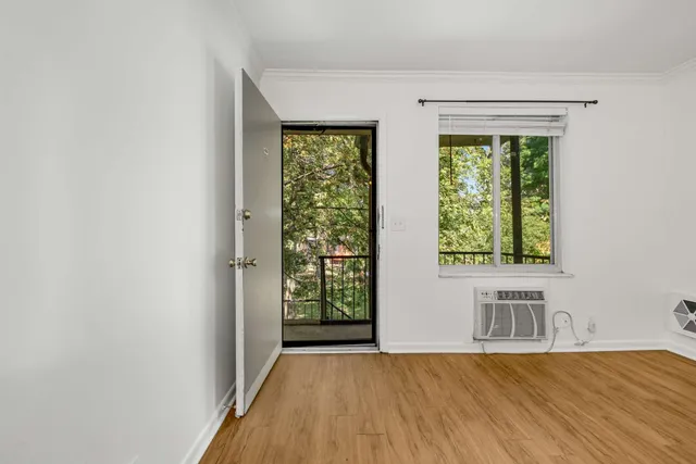 a view of empty room with wooden floor and fan