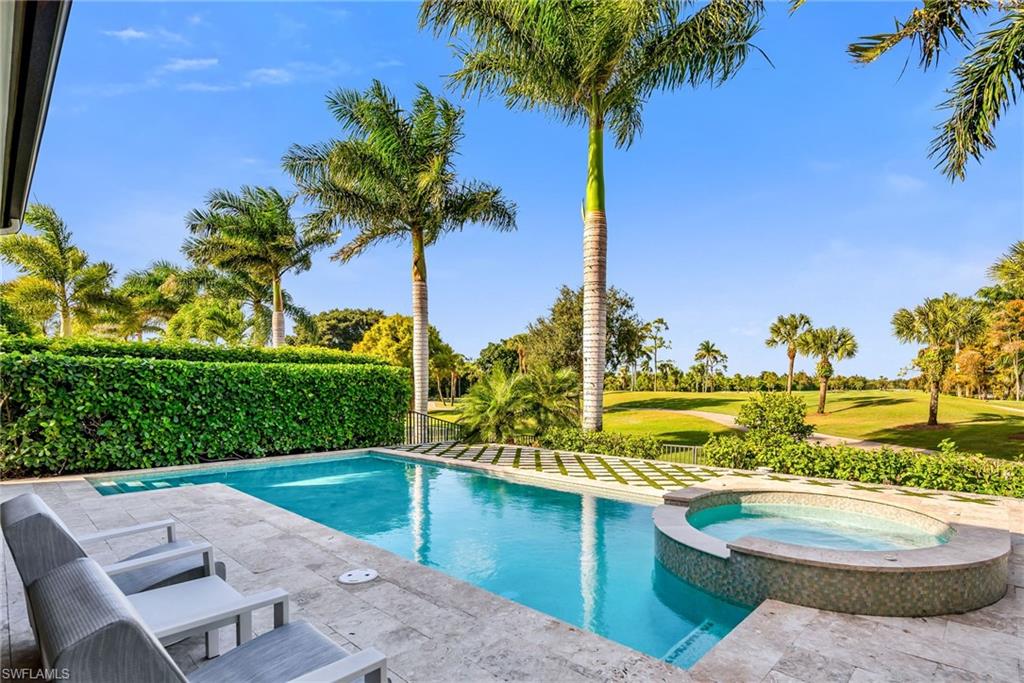 1671 Vinland Way Naples, FL 34105 - Photo 13 of 50 a view of a swimming pool with a lawn chairs under an umbrella next to yard