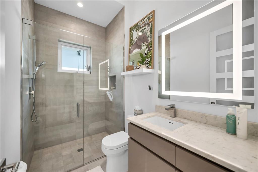 1671 Vinland Way Naples, FL 34105 - Photo 22 of 50 a bathroom with a granite countertop sink a toilet and shower