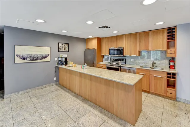 a kitchen with stainless steel appliances a stove a sink a refrigerator a microwave oven and a refrigerator