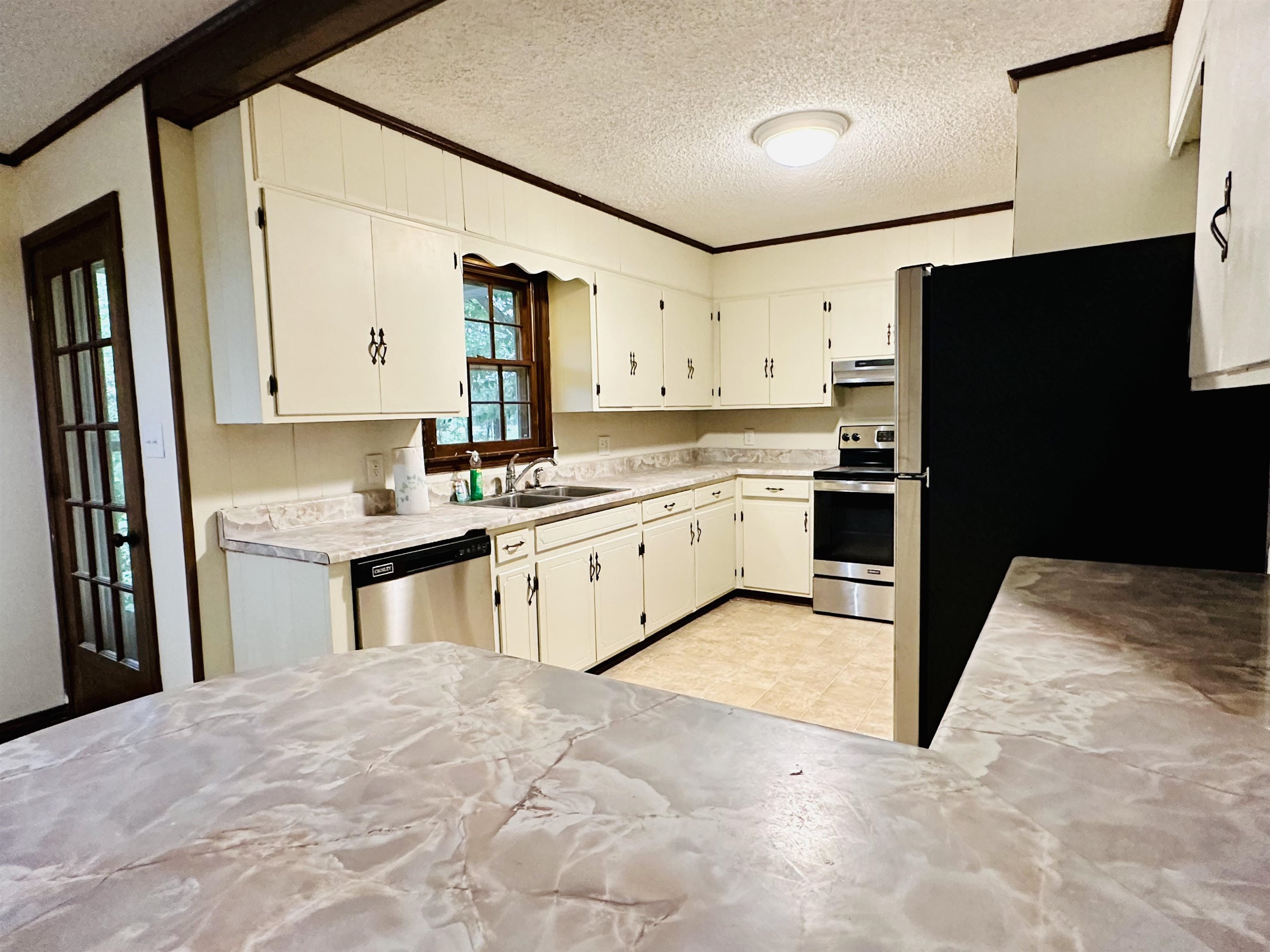 2733 New Hope Road Guys, TN 38339 - Photo 6 of 25 a kitchen with granite countertop a refrigerator sink stove and white cabinets