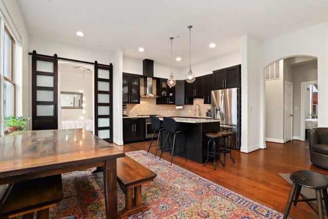 140 Ridge Avenue, Unit 2W Evanston, IL 60202 - Photo 11 of 36 a kitchen with stainless steel appliances kitchen island granite countertop a refrigerator a stove a sink a dining table and chairs with wooden floor