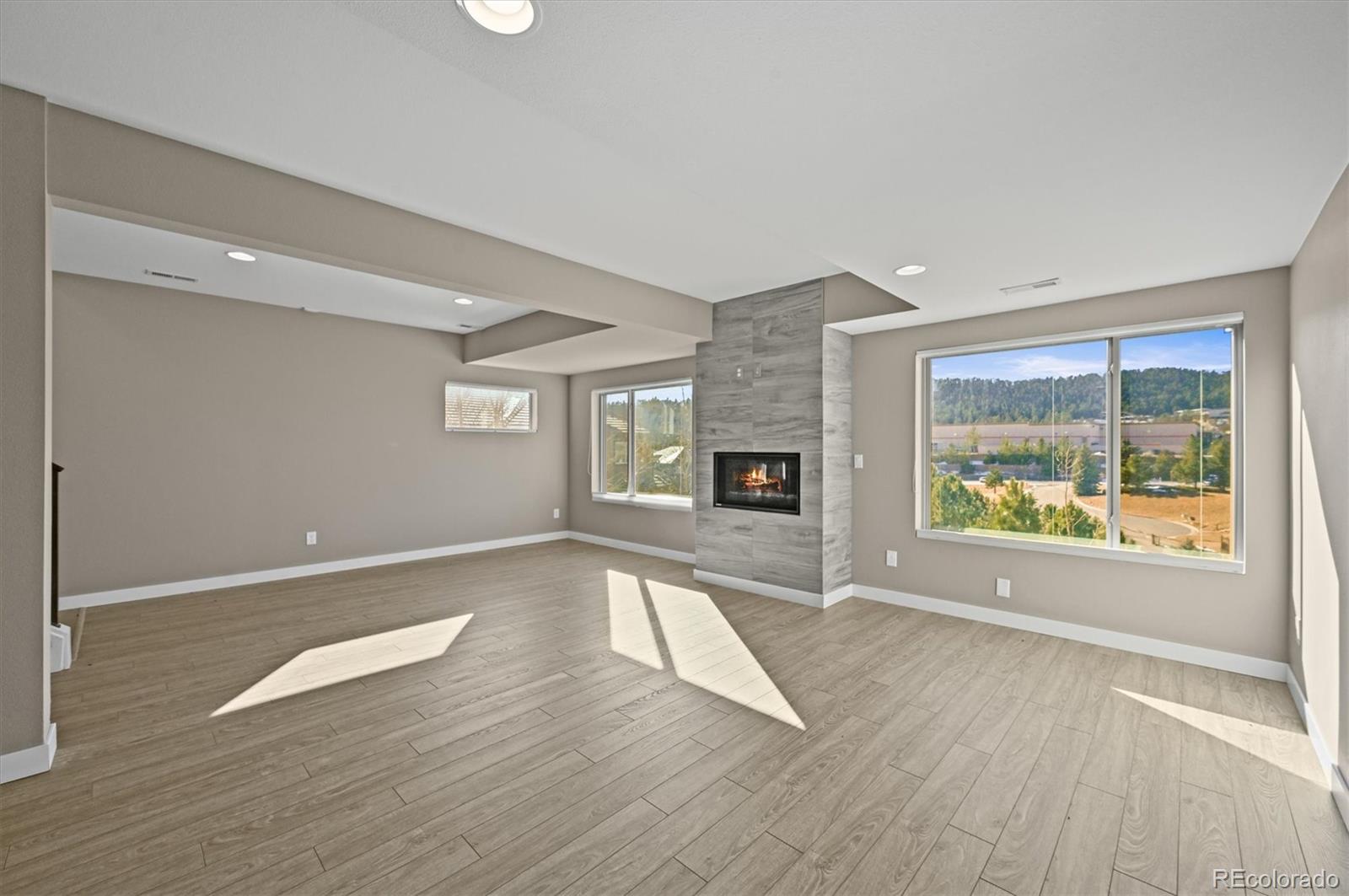 28424 Tepees Way Evergreen, CO 80439 - Photo 31 of 47 an empty room with wooden floor and fireplace
