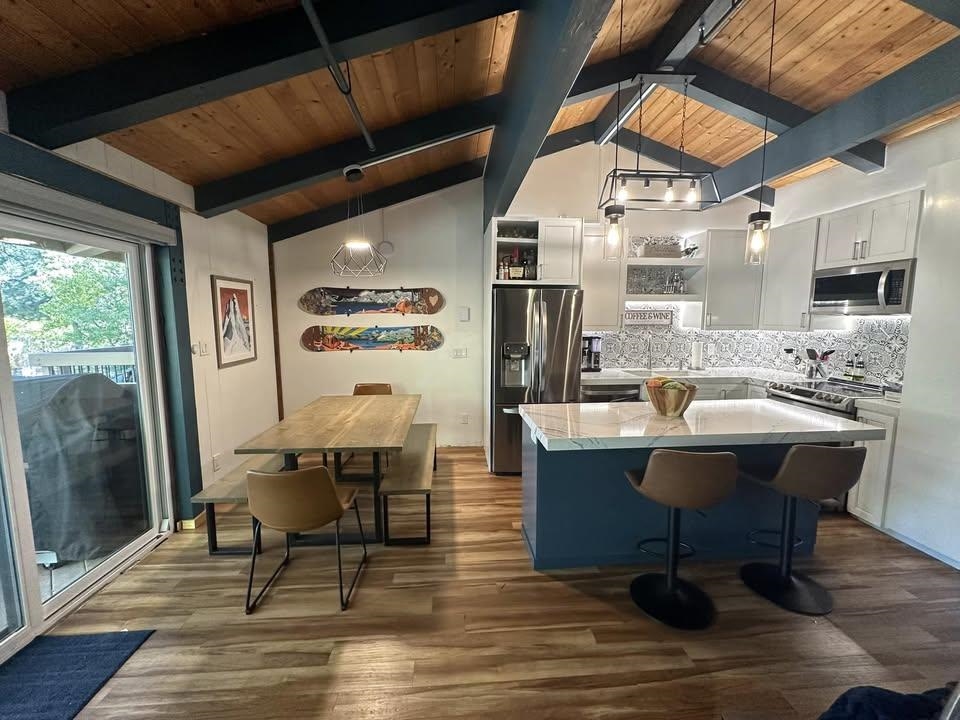 3252 Chateau Road, Unit 43 Mammoth Lakes, CA 93546 - Photo 1 of 29 Vaulted wood-paneled ceiling with exposed beams, wood-finish flooring, white cabinetry, stainless steel appliances, and a kitchen island with a light-toned countertop