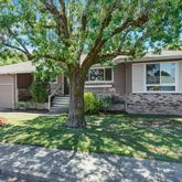a view of a house with a yard and large tree