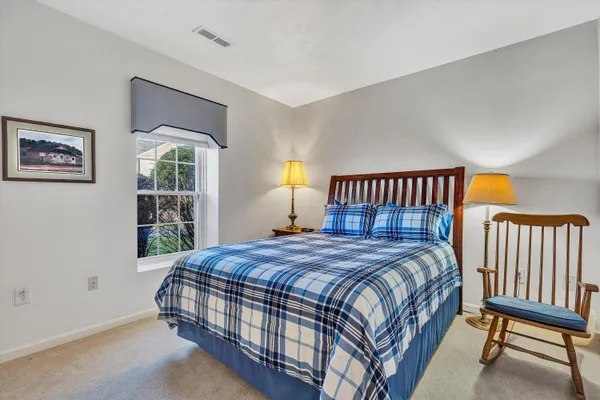 a bedroom with a bed a painting on the wall and a window