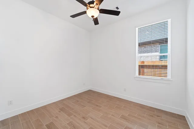 an empty room with a window and a fan