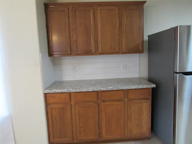 a kitchen with granite countertop cabinets and refrigerator