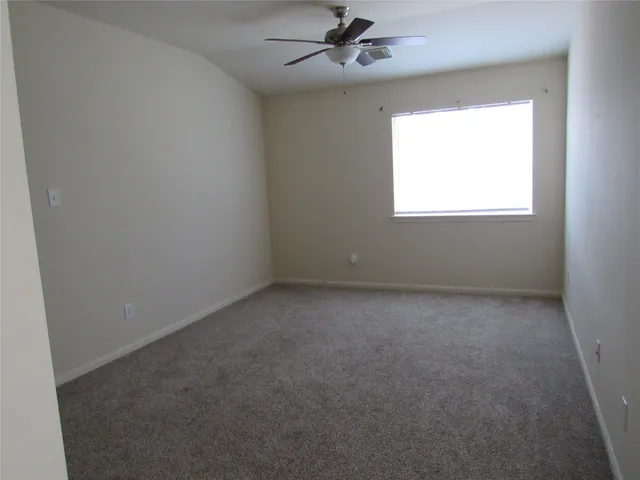 an empty room with a window and a fan