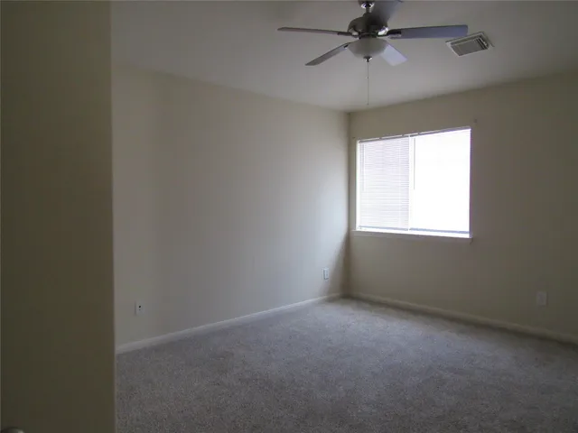an empty room with a window and a fan