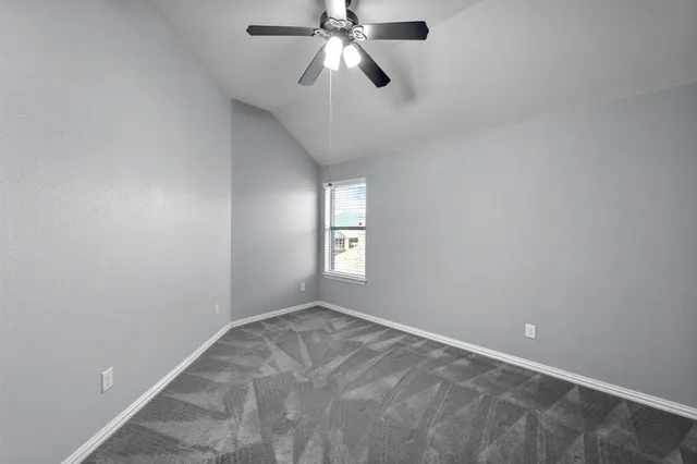 a view of an empty room and window with a fan