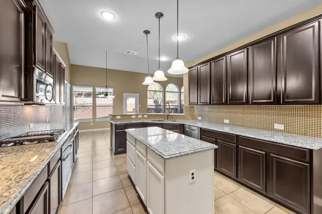 a kitchen with granite countertop stainless steel appliances a sink stove and cabinets