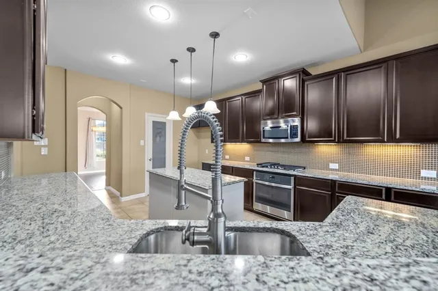 a kitchen with stainless steel appliances granite countertop a sink a stove and a refrigerator