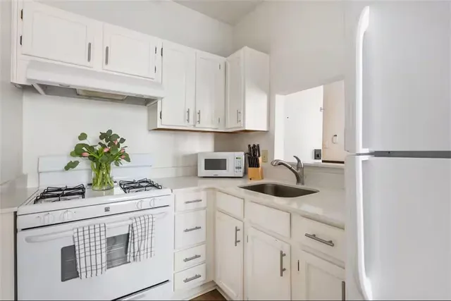 a kitchen with white cabinets and appliances