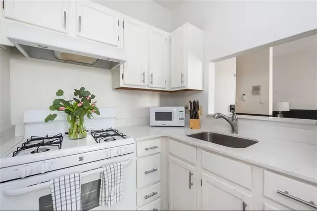 a kitchen with stainless steel appliances white cabinets and wooden floor