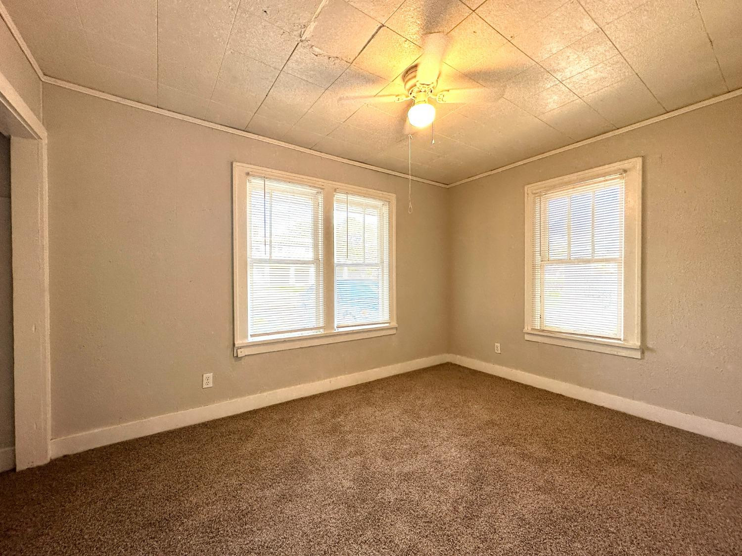 2117 15th Street, Unit A Lubbock, TX 79401 - Photo 6 of 11 an empty room with windows and chandelier fan