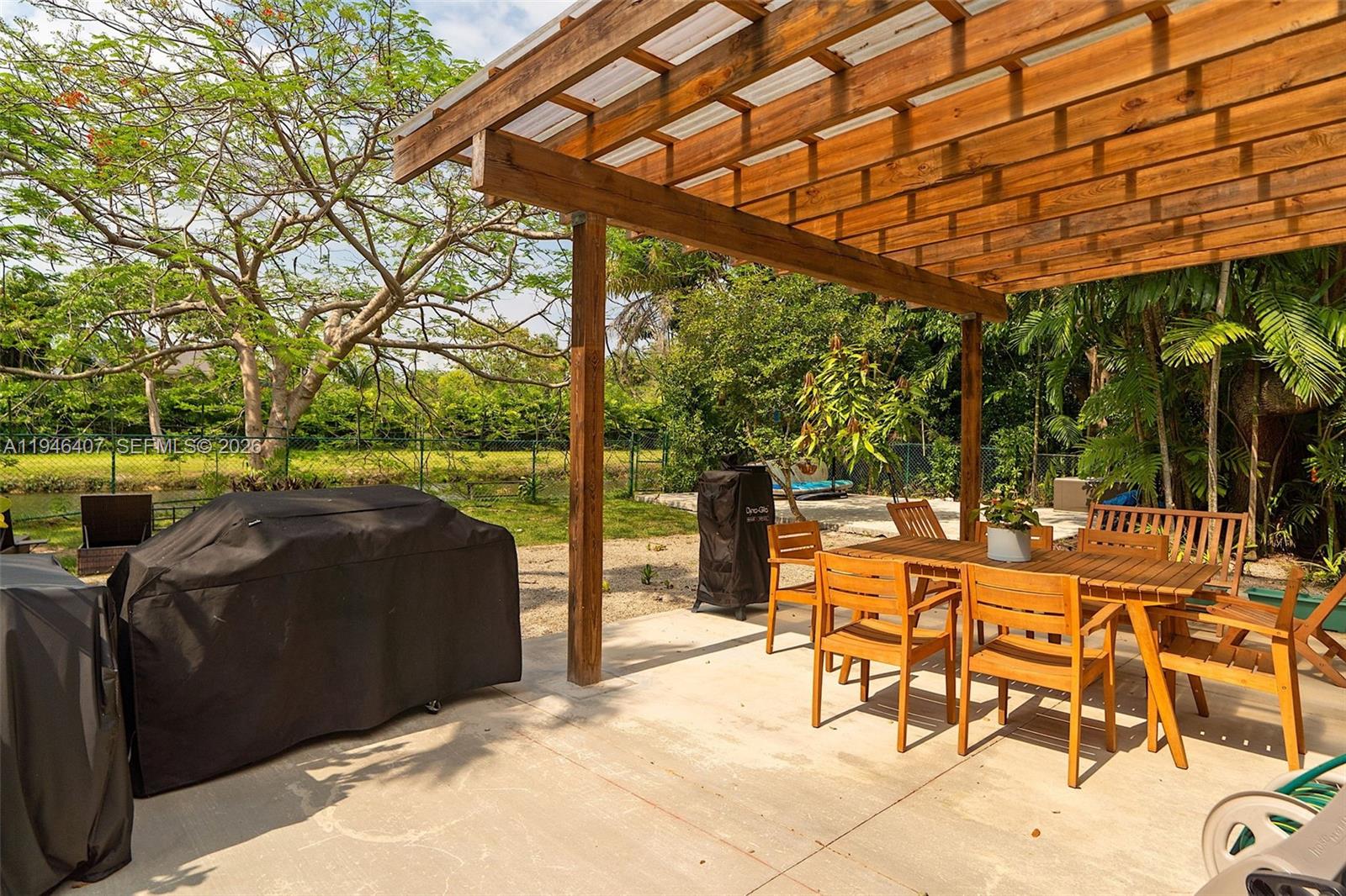 5845 Southwest 88th Street Miami, FL 33156 - Photo 23 of 25 a view of a patio with table and chairs under an umbrella with a big yard