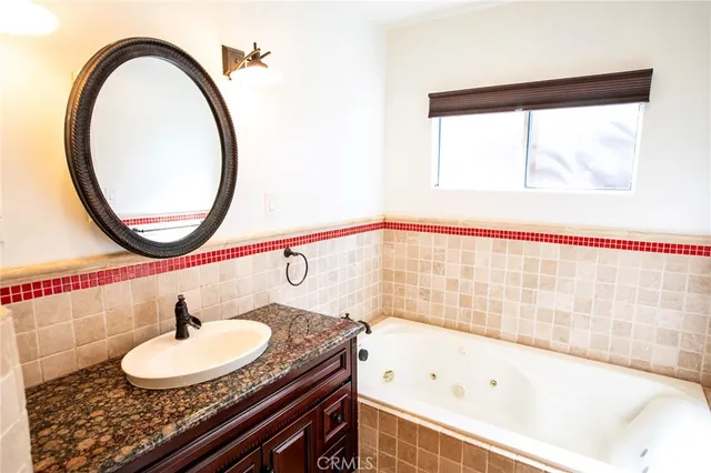 a bathroom with a granite countertop sink a mirror and a bathtub