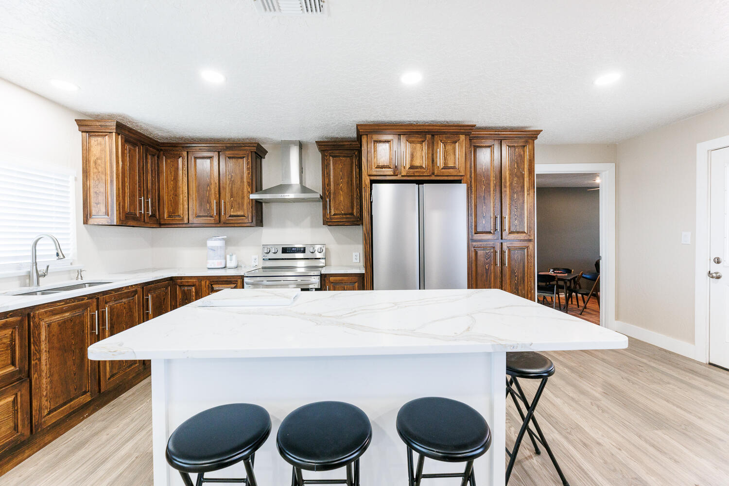 3807 East 3rd Street Lubbock, TX 79403 - Photo 10 of 35 a kitchen with stainless steel appliances a dining table chairs refrigerator and sink
