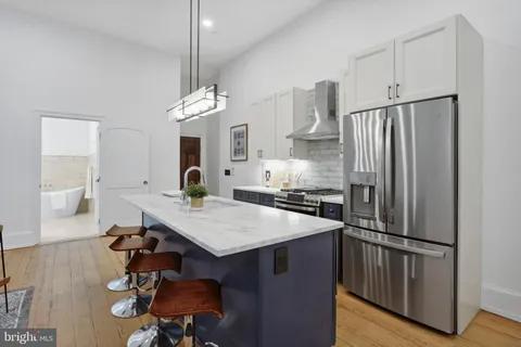 a kitchen with stainless steel appliances a table and chairs in it
