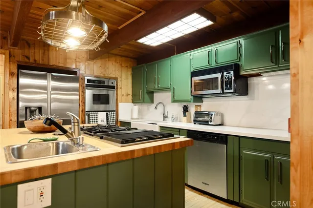 a kitchen with stainless steel appliances a sink a stove a microwave a refrigerator and cabinets