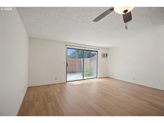 a view of an empty room with kitchen and a window