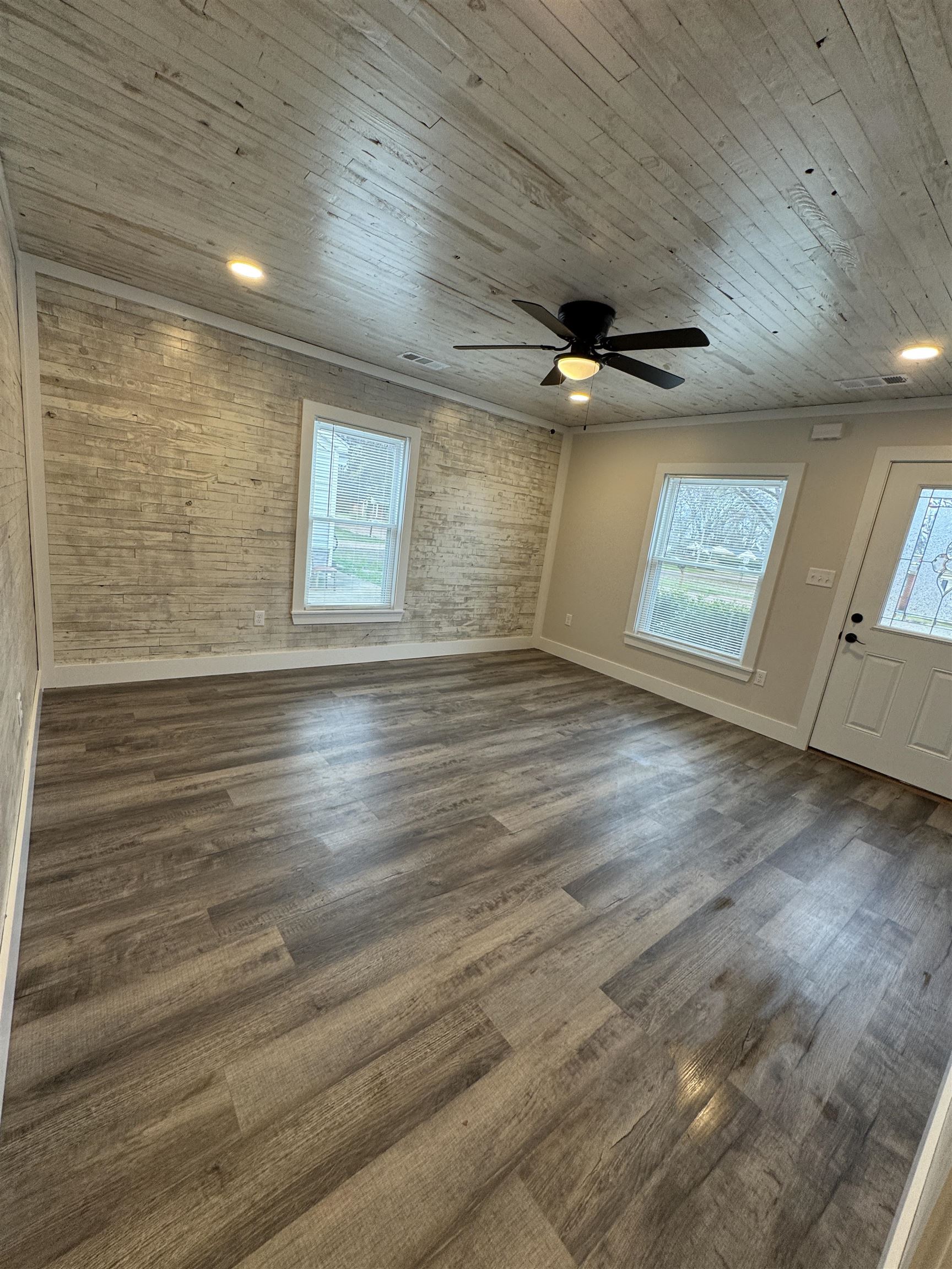 311 East Ripley Avenue Covington, TN 38019 - Photo 1 of 37 Unfurnished living room with a ceiling fan, dark wood-type flooring, wooden ceiling, brick wall, and wooden walls