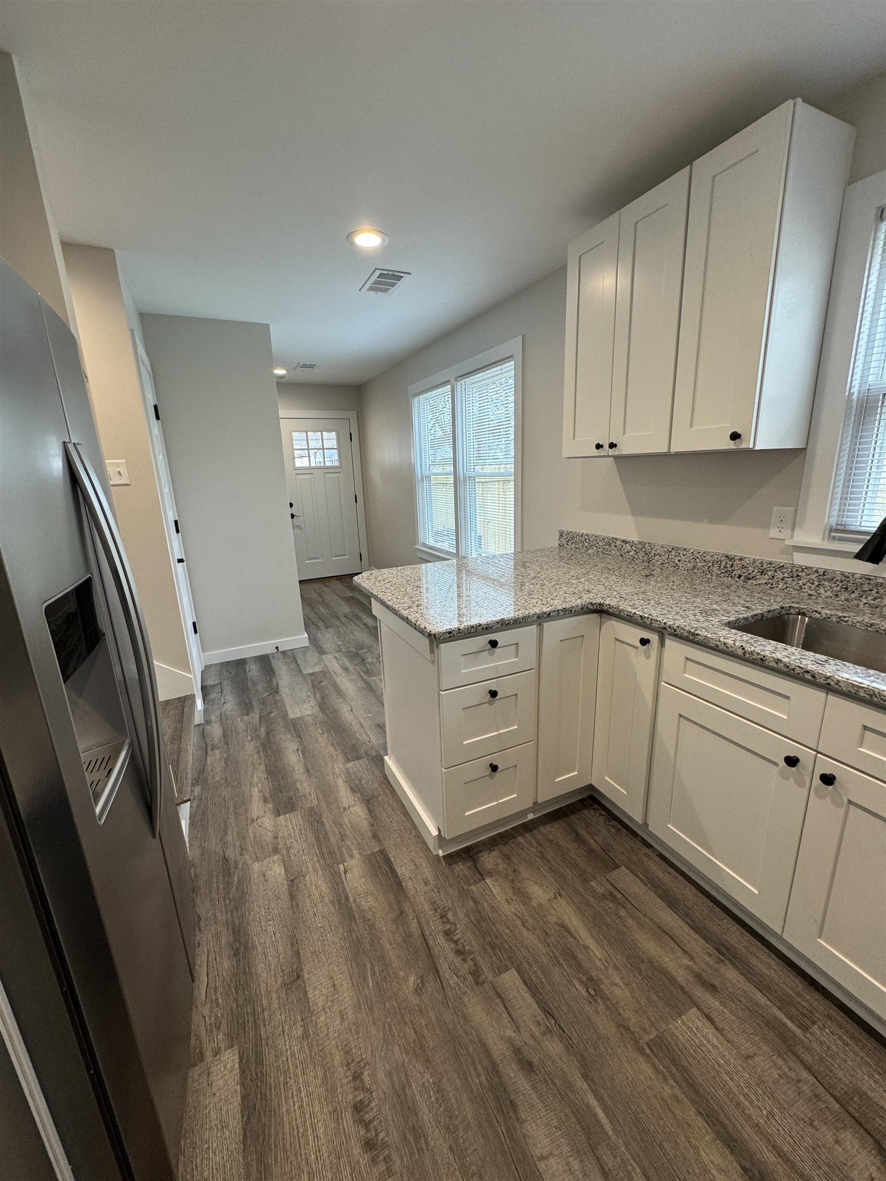 311 East Ripley Avenue Covington, TN 38019 - Photo 11 of 37 Kitchen with stainless steel fridge, white cabinetry, lazy susan #1, light granite countertops, dark wood-style flooring, and a peninsula