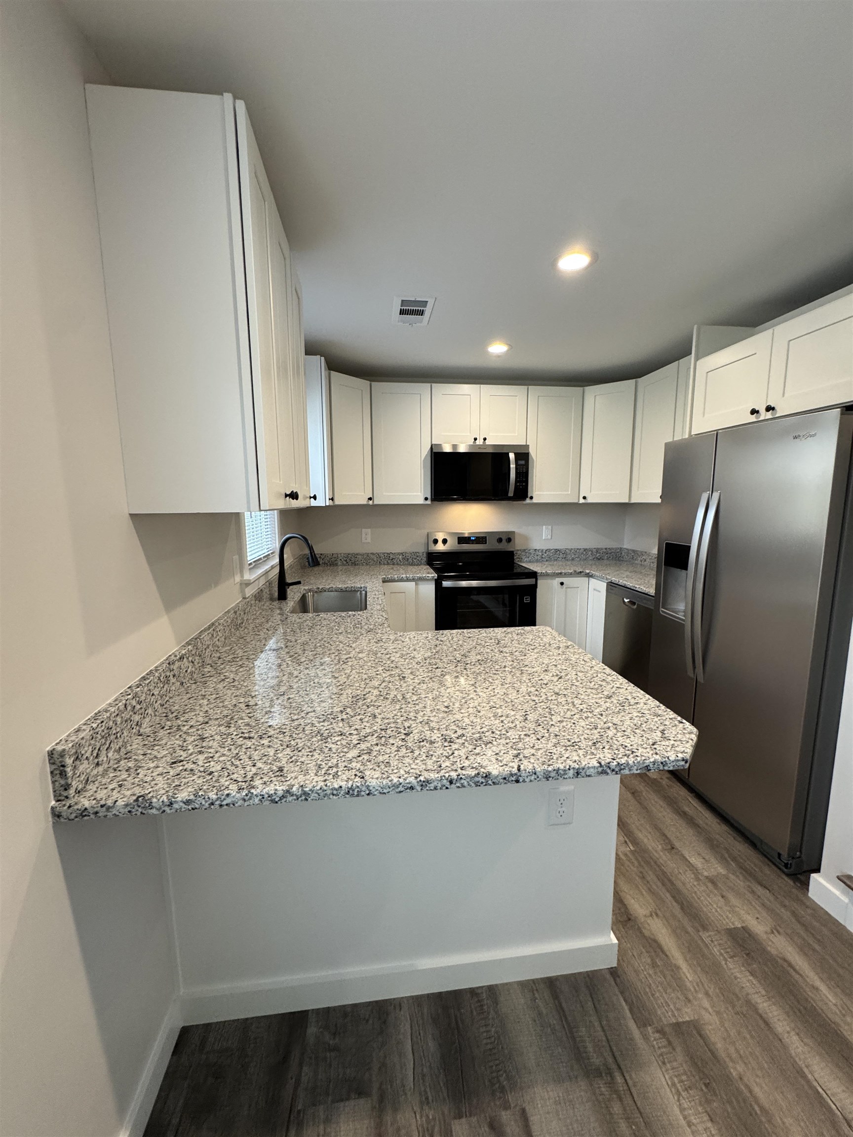 311 East Ripley Avenue Covington, TN 38019 - Photo 16 of 37 Kitchen with light granite counters, stainless steel appliances, white cabinets, a peninsula, and dark wood-style flooring