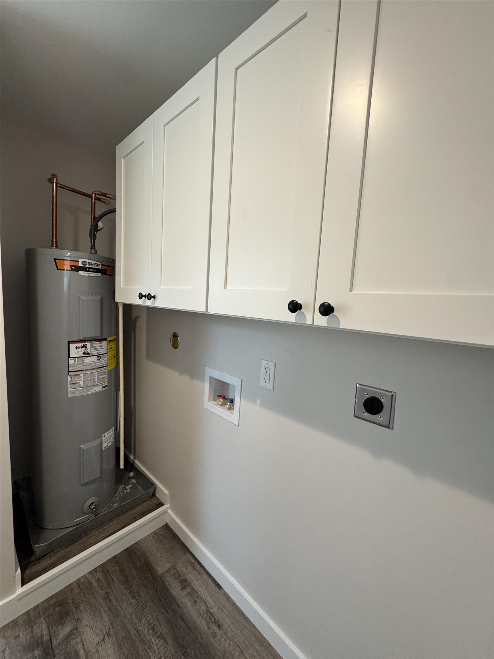 311 East Ripley Avenue Covington, TN 38019 - Photo 28 of 37 Laundry area featuring cabinet space, washer hookup, electric water heater, dark wood-style floors, and electric dryer hookup