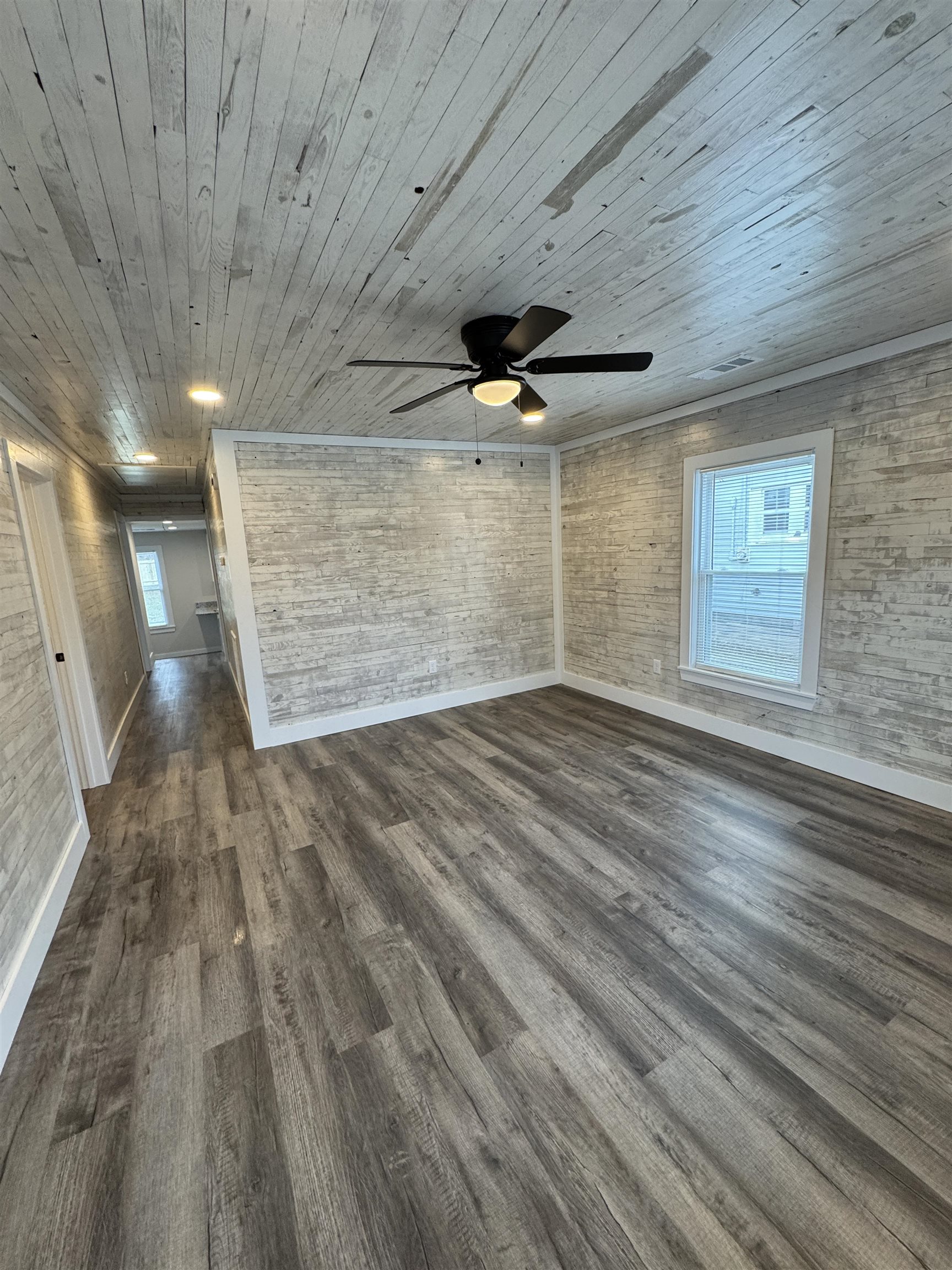 311 East Ripley Avenue Covington, TN 38019 - Photo 3 of 37 Unfurnished room featuring dark wood-style floors, a ceiling fan, and wood walls