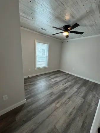 an empty room with wooden floor ceiling fan and windows