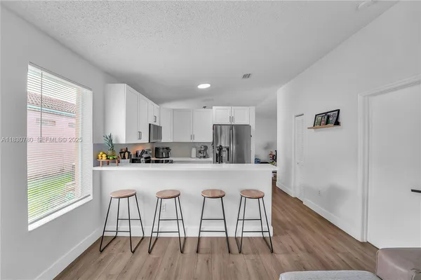 a kitchen with stainless steel appliances a dining table chairs and wooden floor