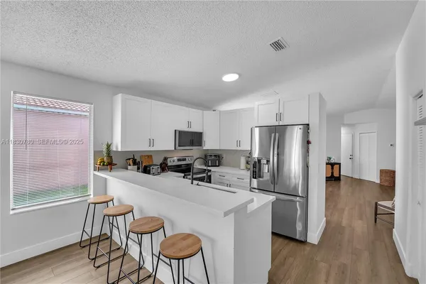 a kitchen with stainless steel appliances a refrigerator and wooden floor