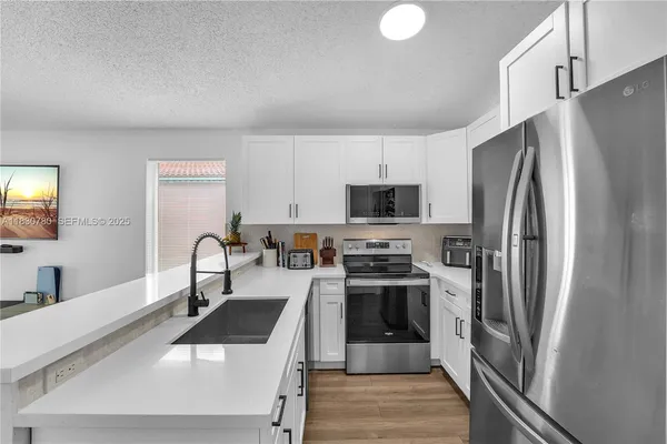 a kitchen with stainless steel appliances a refrigerator sink and white cabinets
