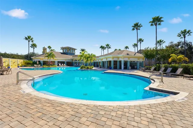 a view of a swimming pool with lawn chairs potted plants