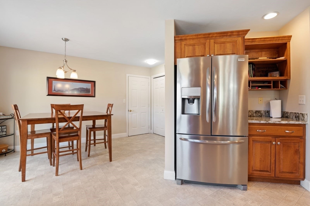 101 Tussock Brook Road, Unit 101 Duxbury, MA 02332 - Photo 5 of 38 a kitchen with stainless steel appliances granite countertop a refrigerator a stove a microwave oven a sink with a dining table and chairs