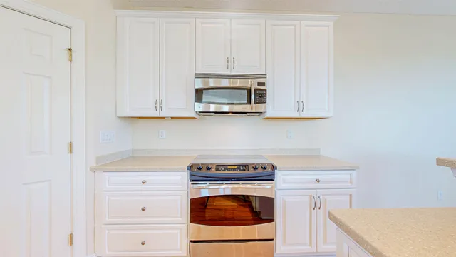 a living room with stainless steel appliances furniture a kitchen view and wooden floor