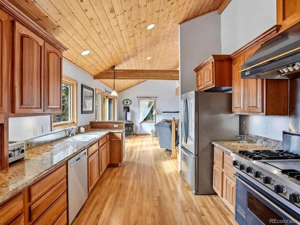 a kitchen with stainless steel appliances granite countertop a stove a sink dishwasher and cabinets with wooden floor