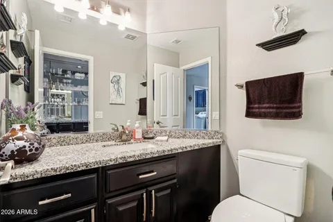 a bathroom with a granite countertop sink a toilet and mirror